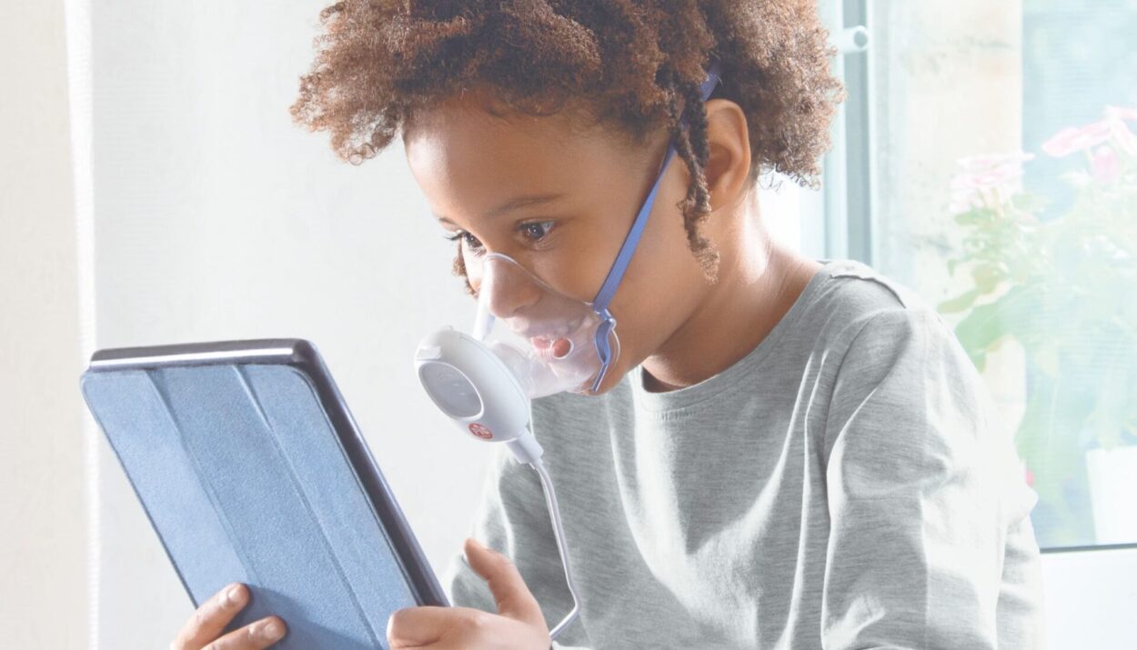 Bambino che utilizza un aerosol Pic Solution per il benessere delle vie respiratorie mentre guarda un tablet.