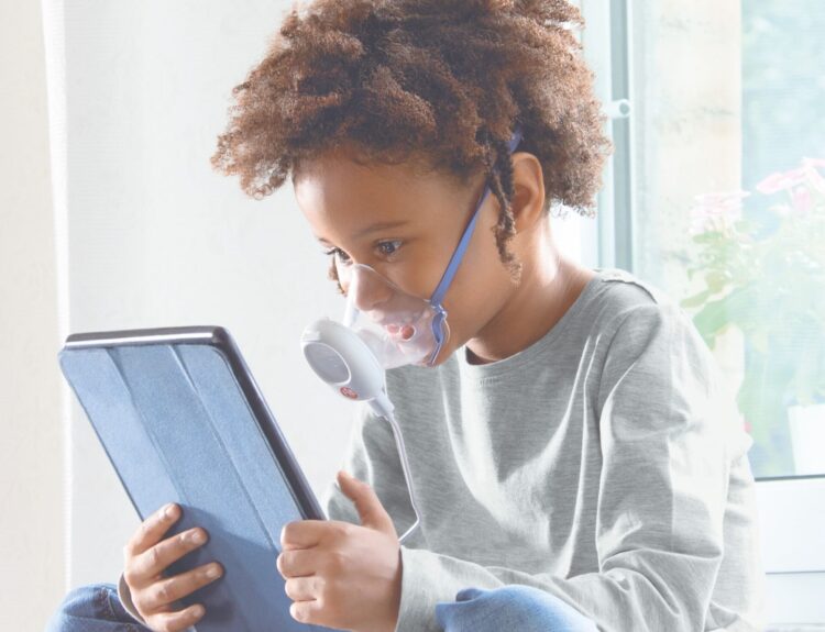 Bambino che utilizza un aerosol Pic Solution per il benessere delle vie respiratorie mentre guarda un tablet.